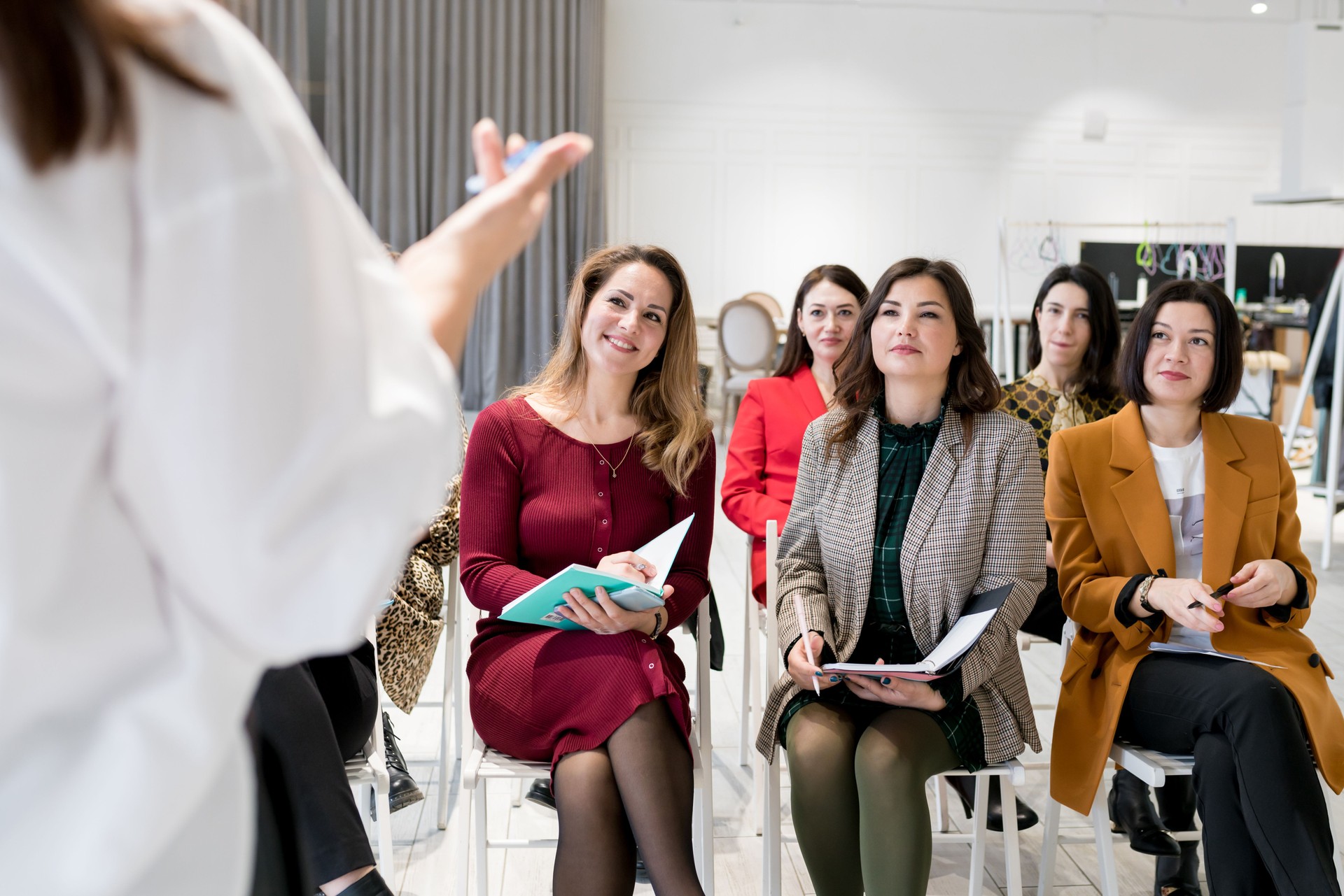 Group of females sitting in the audience for business training. Women outlining coach speech in notebook. People attending personal development seminar or conference. Lifelong learning concept