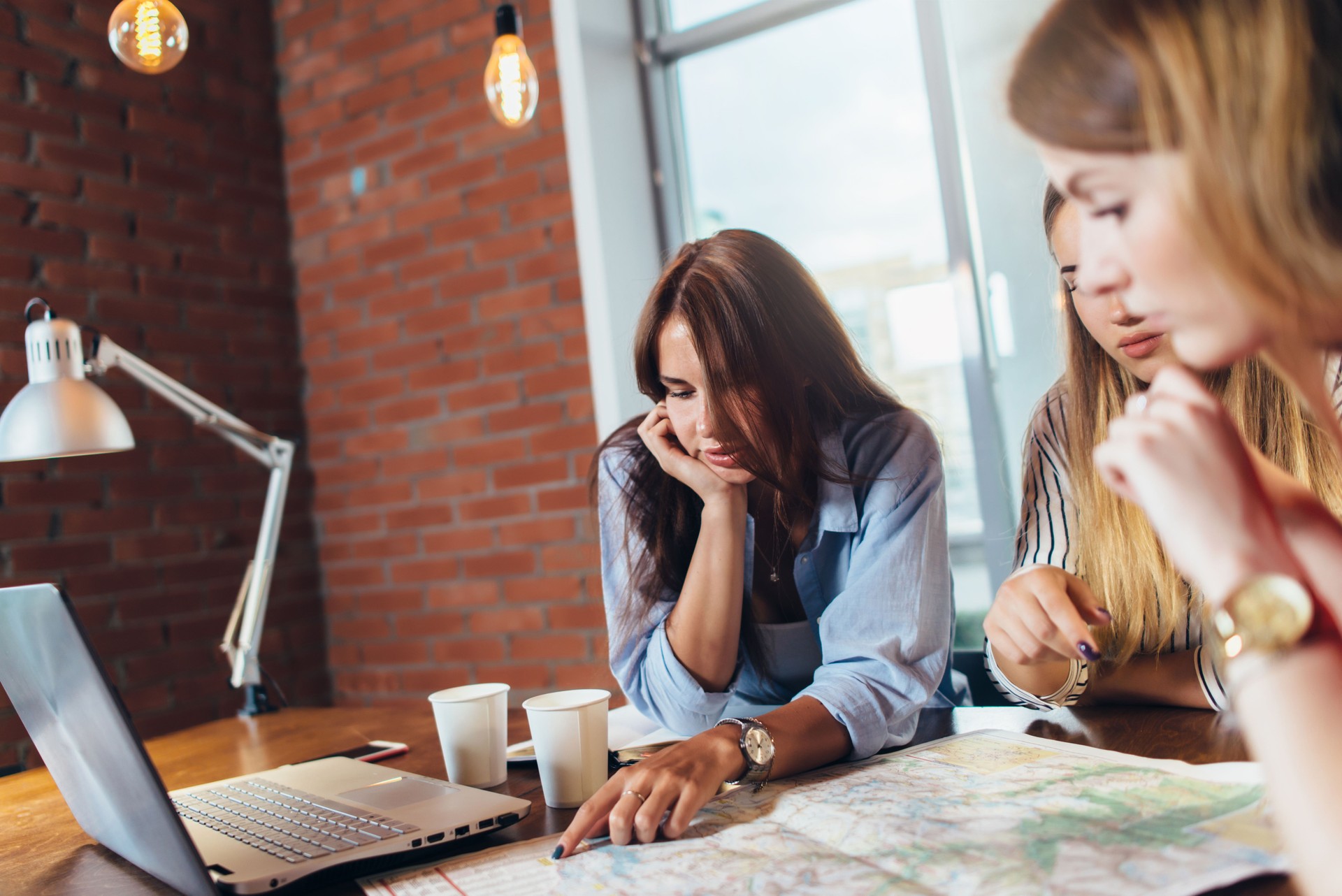 Female office workers planning vacation using map